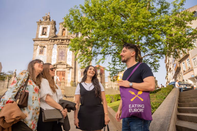 A private group smiling and walking together along an old-world European stone street with traditional tall buildings.